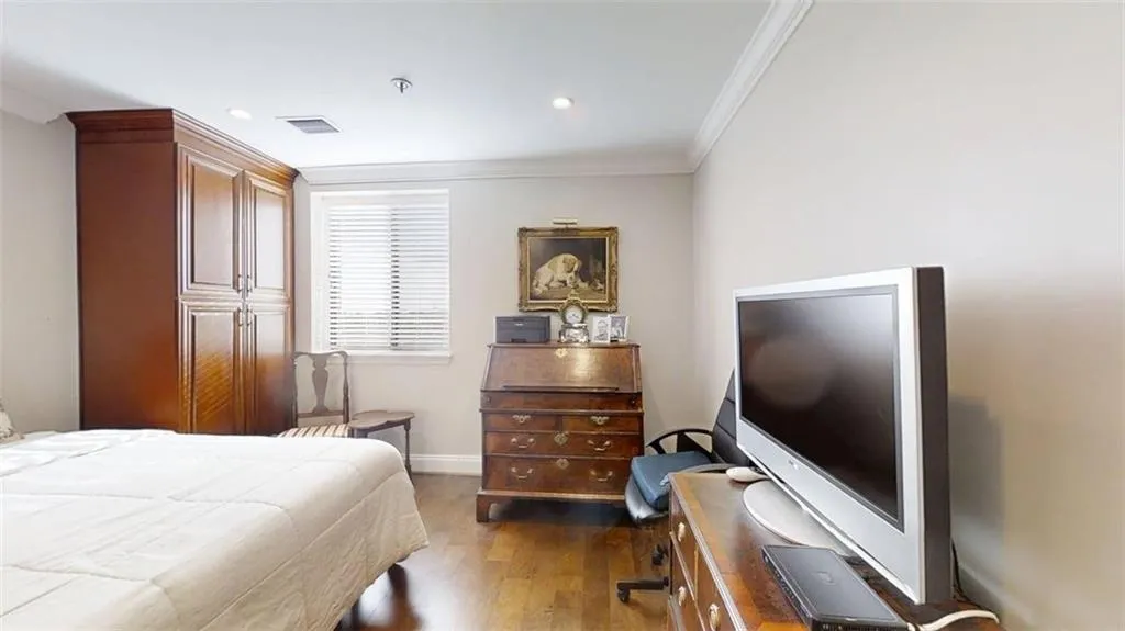 Bedroom with ornamental molding, wood finished floors, and recessed lighting