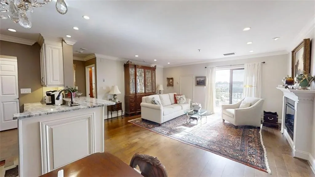 Living area featuring light wood-type flooring, recessed lighting, crown molding, and a glass covered fireplace
