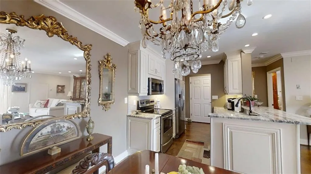 Kitchen featuring a chandelier, appliances with stainless steel finishes, recessed lighting, white cabinetry, and crown molding