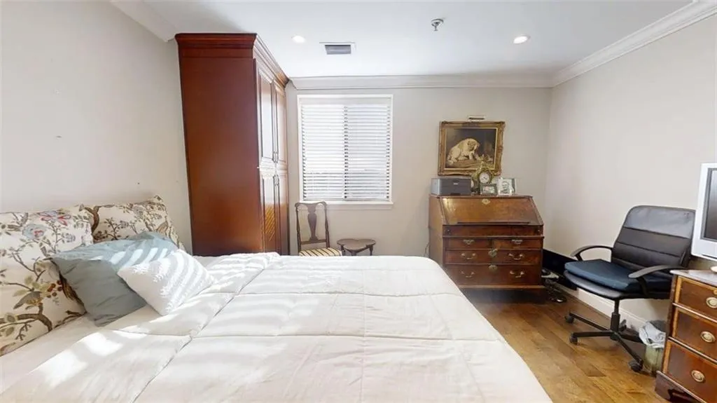 Bedroom with wood finished floors and crown molding