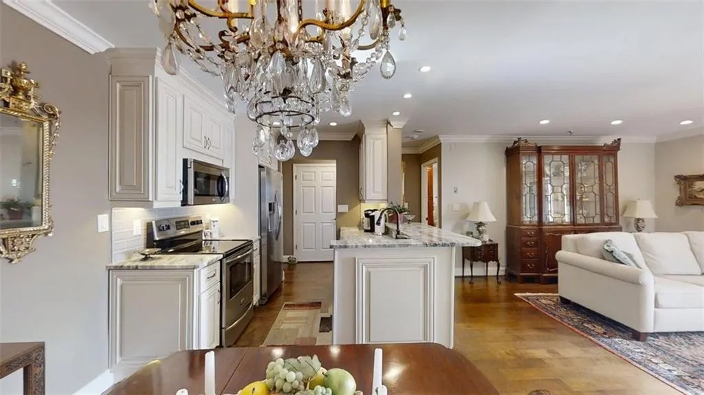 Kitchen with appliances with stainless steel finishes, crown molding, recessed lighting, wood finished floors, and open floor plan