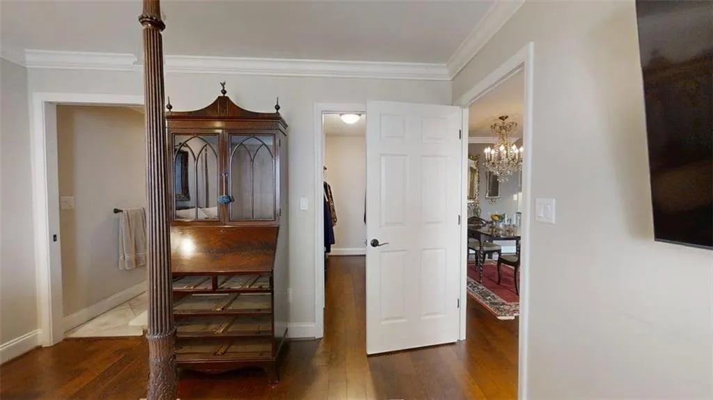 Hallway featuring wood finished floors, a chandelier, and crown molding