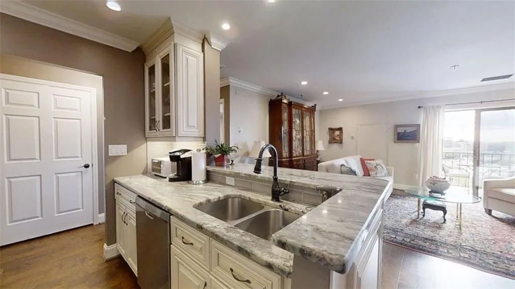 Kitchen with open floor plan, recessed lighting, dishwasher, glass insert cabinets, and light stone counters