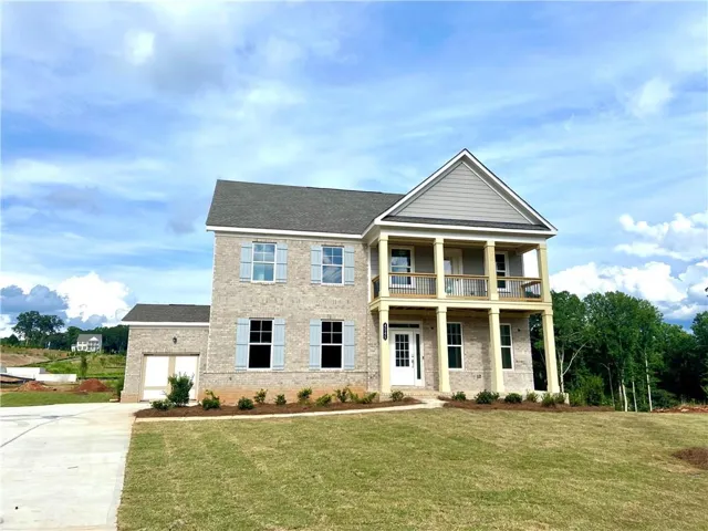 Two-story residence featuring light-colored brick, a two-car garage, and a two-story porch with wood railings