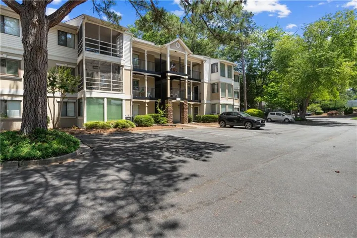 Multi-story building with screened balconies, open-air balconies, and a stone facade accent