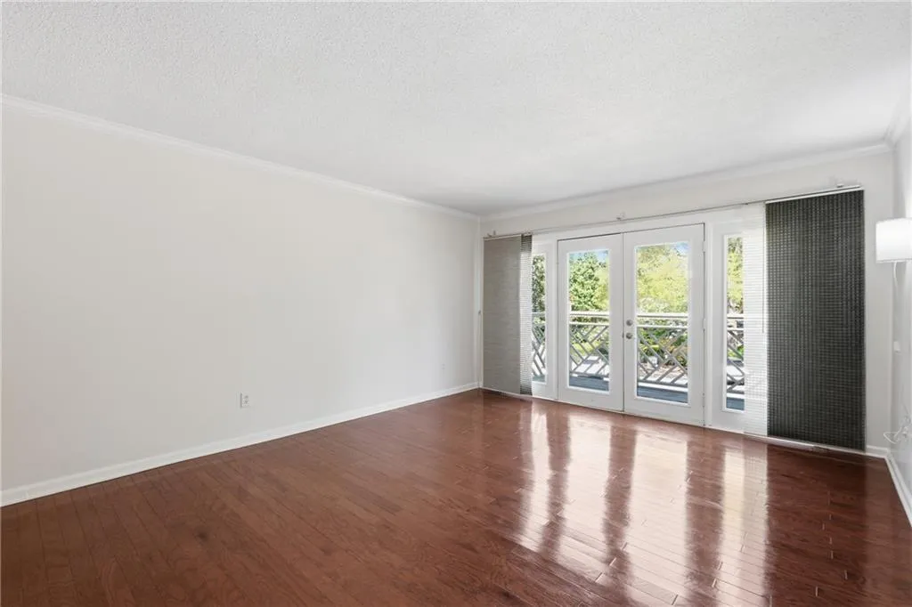 Empty room featuring french doors, dark wood finished floors, crown molding, and a textured ceiling
