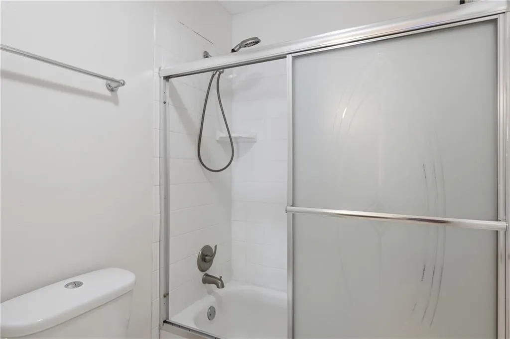 Bathroom featuring toilet and enclosed tub / shower combo