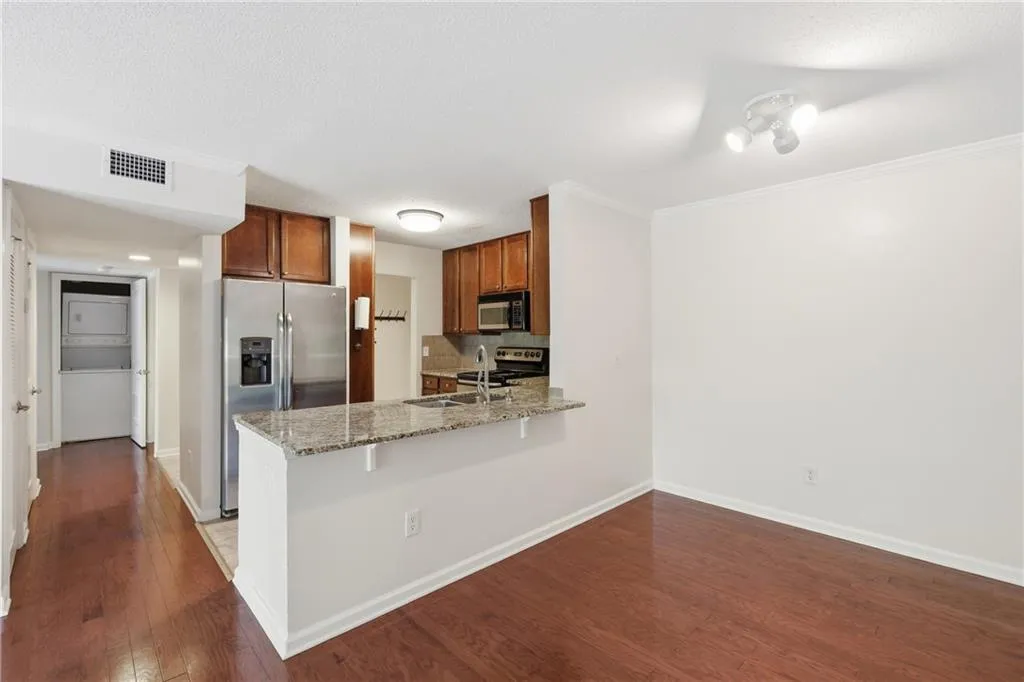 Kitchen with light stone countertops, stainless steel appliances, a peninsula, crown molding, and a breakfast bar