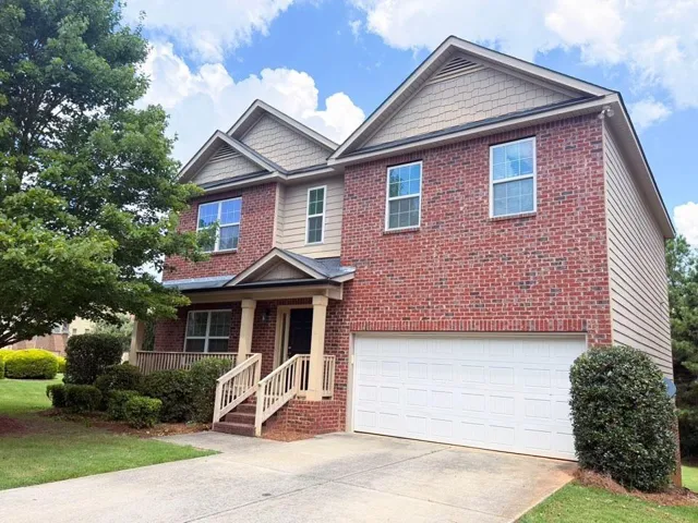Two-story residence featuring a brick facade with complementary siding and shingle accents