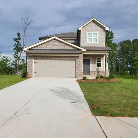 Contemporary home featuring brick and shake siding, a two-car garage, a covered front porch, and a concrete driveway
