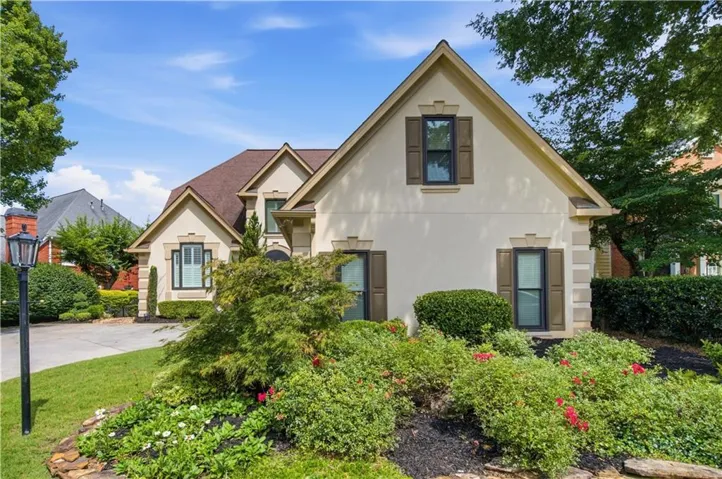 Stucco exterior residence featuring gabled rooflines and a paved driveway