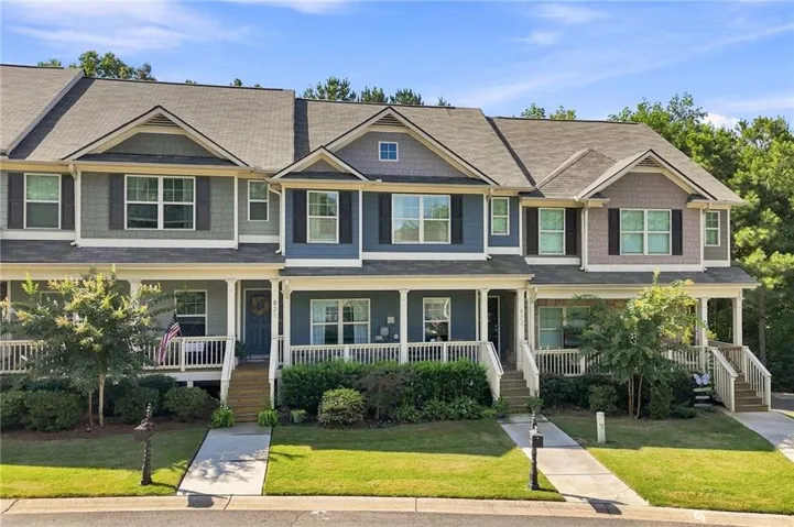 Craftsman-style townhome featuring multi-pane windows, front porches with white railings, and mature landscaping