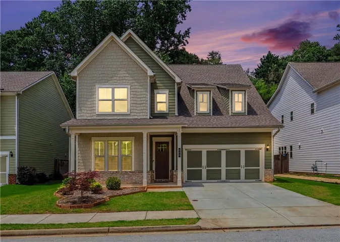 Two-story residence featuring a covered front porch, a two-car garage, and dormer windows