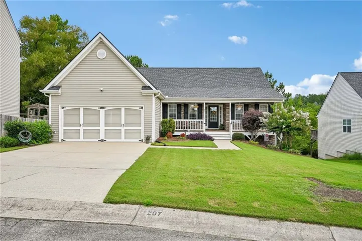 Siding exterior with a covered porch, attached garage, and a concrete driveway