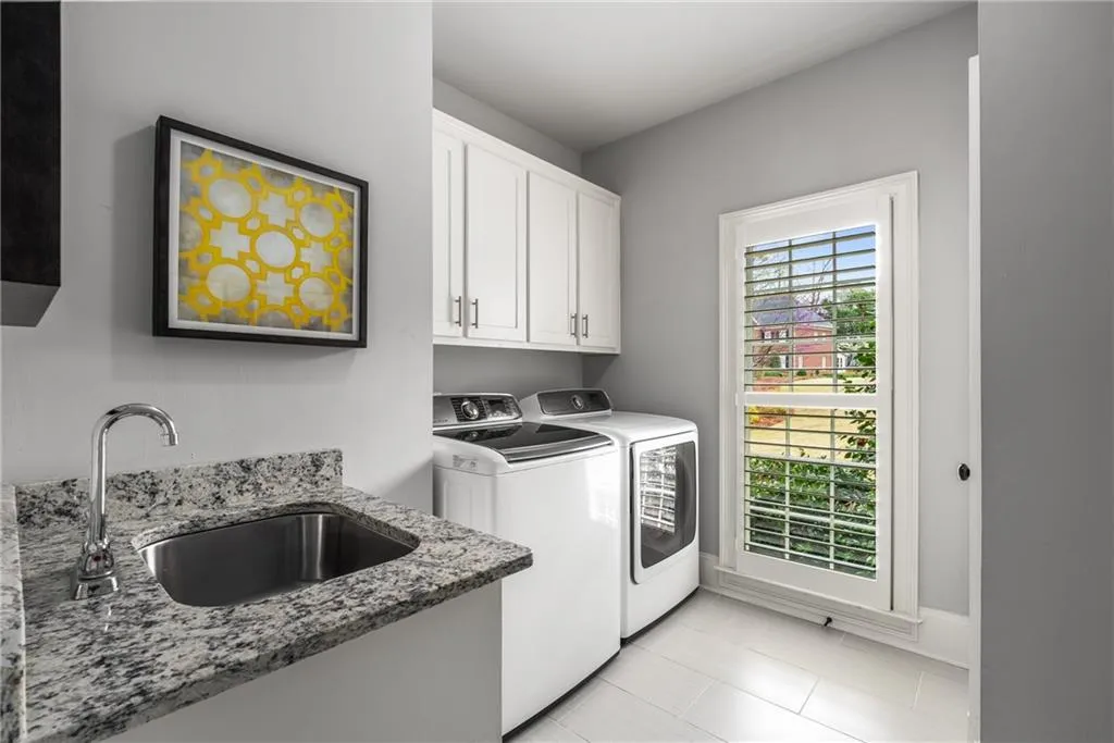 Washroom with baseboards, a sink, washer and dryer, cabinet space, and light tile patterned floors