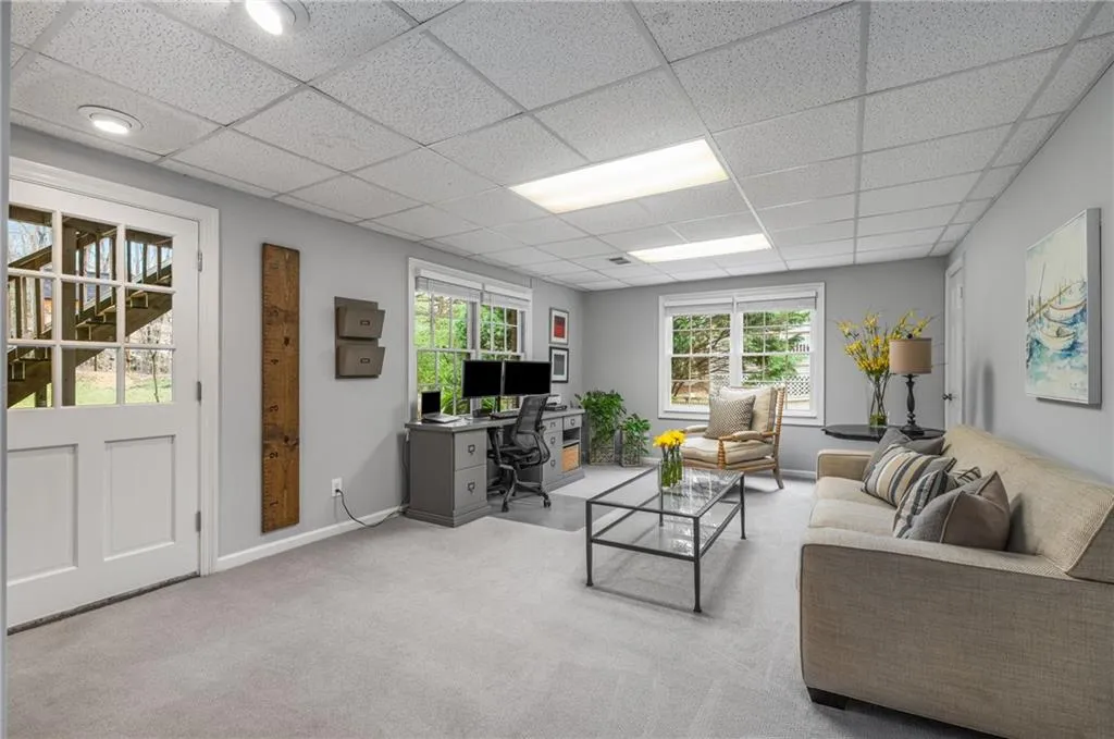 Carpeted living area featuring baseboards and a paneled ceiling