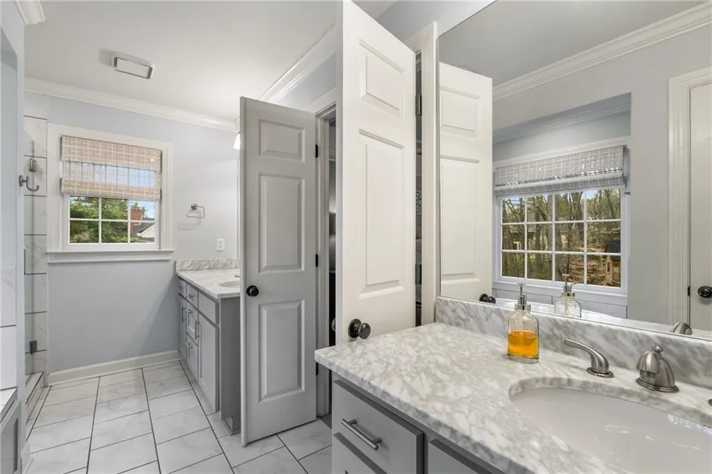 Bathroom with marble finish floor, vanity, crown molding, and baseboards