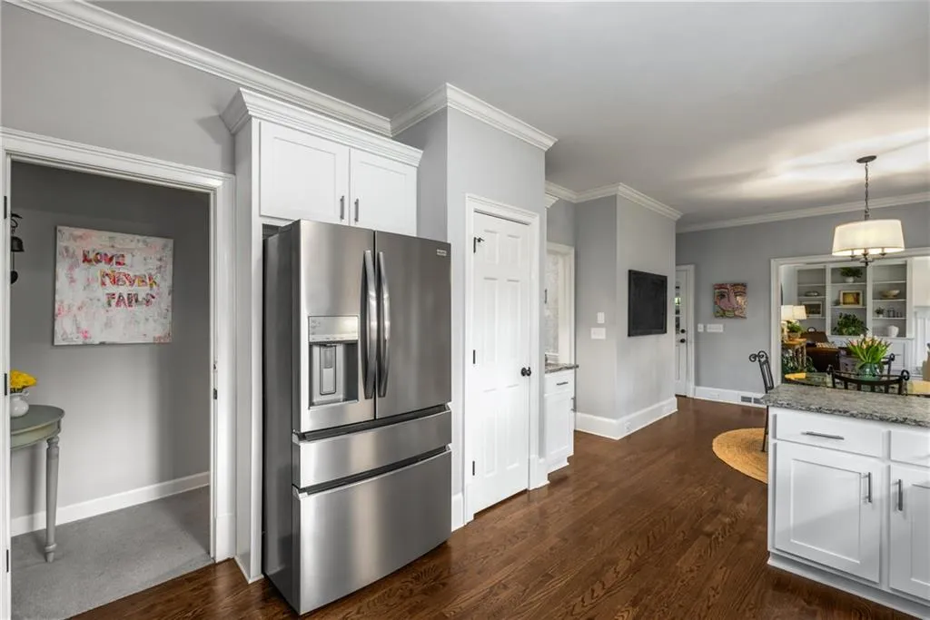 Kitchen featuring crown molding, stone counters, stainless steel fridge with ice dispenser, white cabinets, and dark wood-style flooring