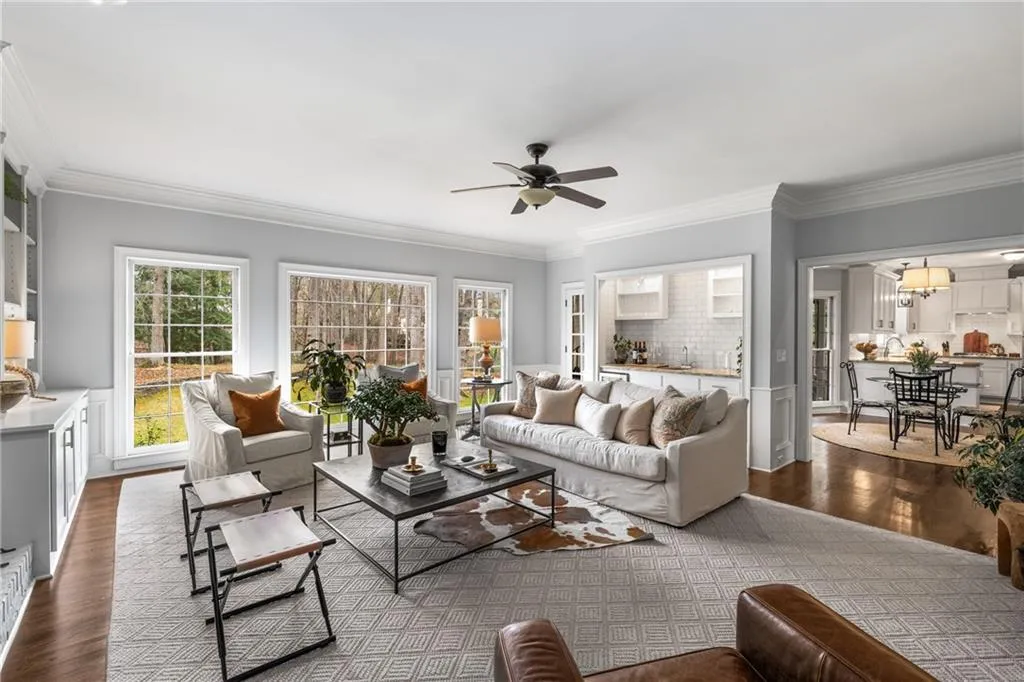 Living area featuring ornamental molding, ceiling fan, and dark wood-type flooring