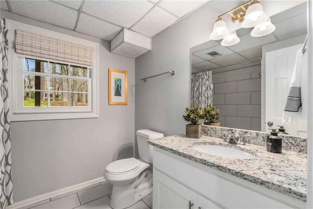 Full bath with toilet, vanity, a notable chandelier, and a paneled ceiling