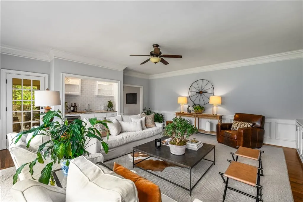 Living area with wainscoting, wood finished floors, ceiling fan, and ornamental molding