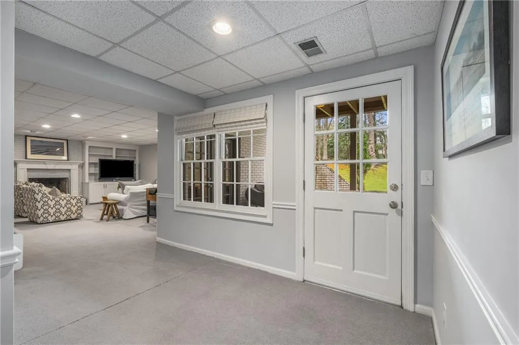 Doorway to outside featuring baseboards, a fireplace, visible vents, and a drop ceiling