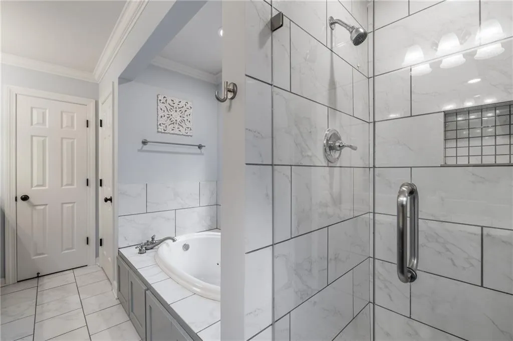 Full bath featuring a tile shower, a garden tub, and crown molding