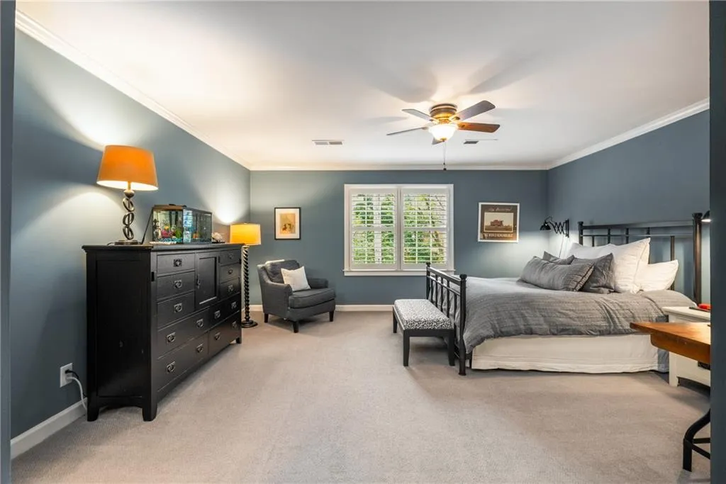 Bedroom featuring light colored carpet, baseboards, visible vents, ceiling fan, and ornamental molding