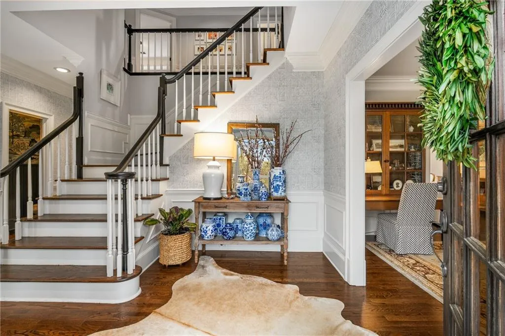 Stairs with wainscoting, a decorative wall, crown molding, and wood finished floors