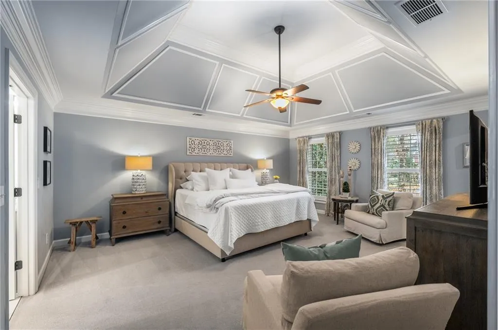 Bedroom featuring coffered ceiling, ornamental molding, baseboards, visible vents, and light carpet