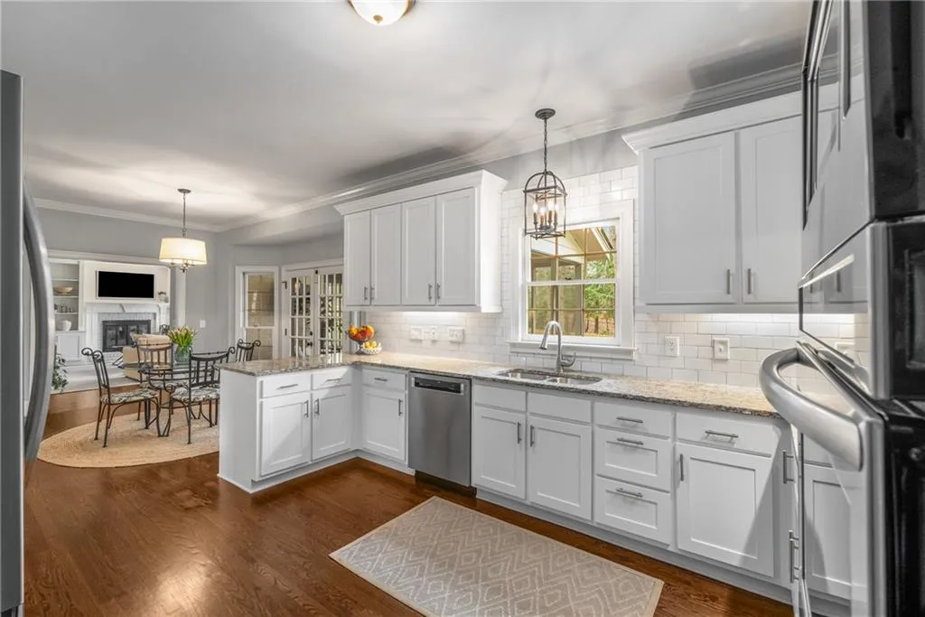Kitchen with dark wood-type flooring, a sink, a peninsula, and appliances with stainless steel finishes