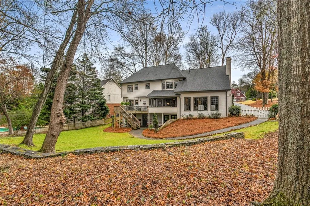 Back of house featuring stairway, a chimney, fence, a sunroom, and a yard