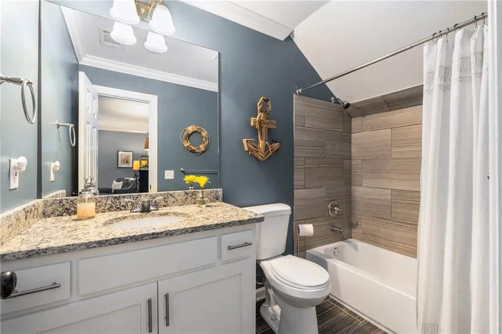 Full bathroom featuring vanity, toilet, ornamental molding, visible vents, and shower / bath combo with shower curtain