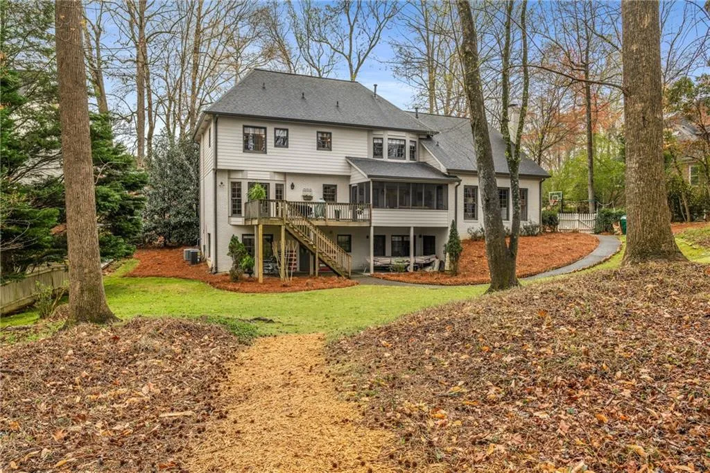 Rear view of property featuring stairway, a shingled roof, a sunroom, central AC unit, and a yard