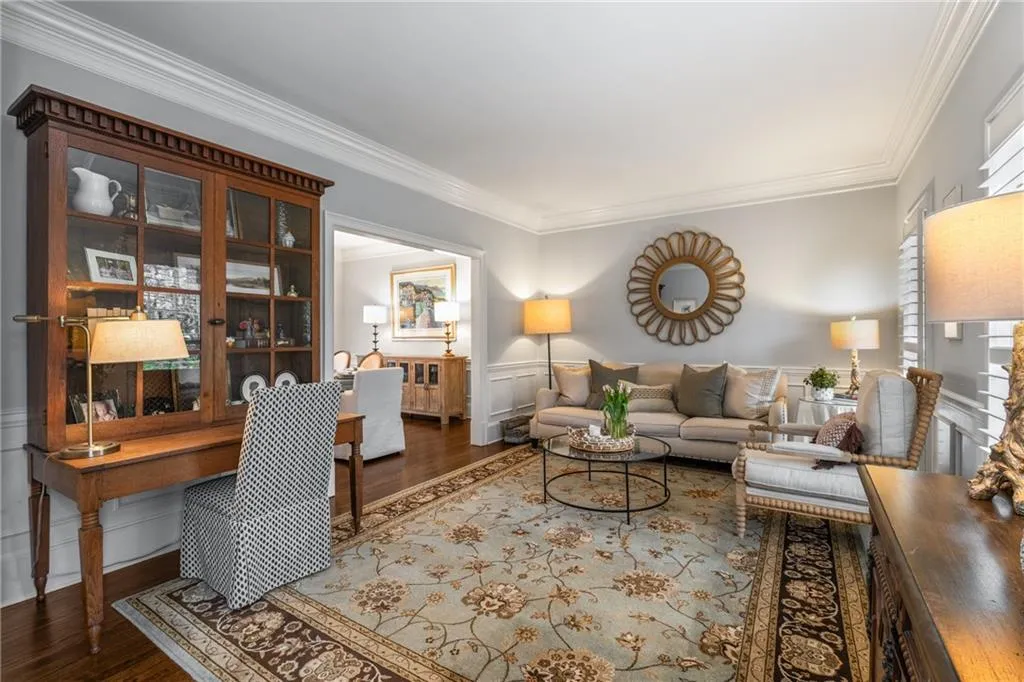 Living room with a wainscoted wall, wood finished floors, and ornamental molding