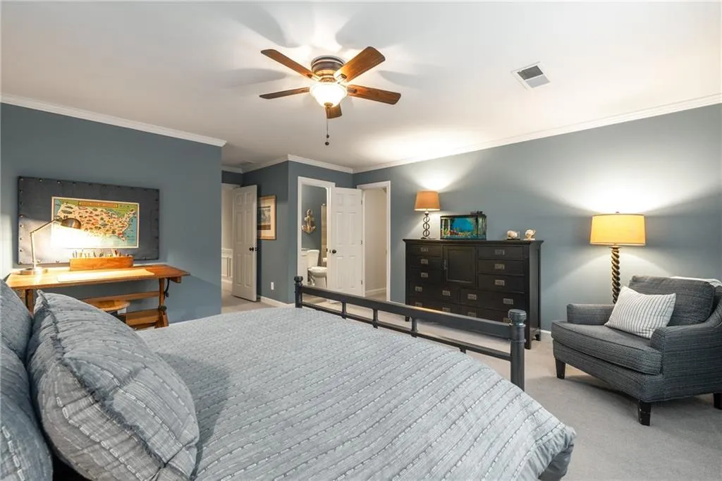 Carpeted bedroom featuring baseboards, a ceiling fan, visible vents, and crown molding