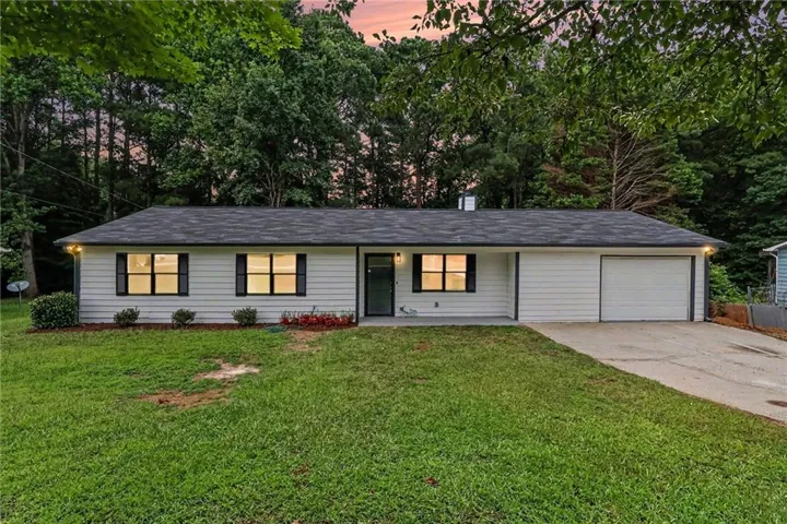 Ranch-style residence featuring white horizontal siding, a dark shingle roof, and a single garage door
