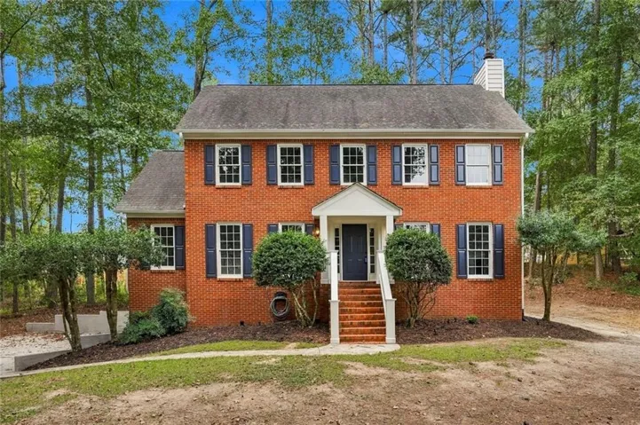 Brick exterior with white window frames and dark shutters