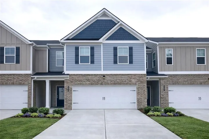 Craftsman house featuring board and batten siding, a garage, driveway, brick siding, and a front lawn