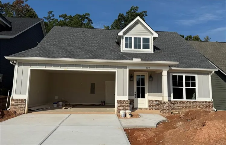 Brick and siding exterior with a dormer window, two-car garage, covered entry, and concrete driveway