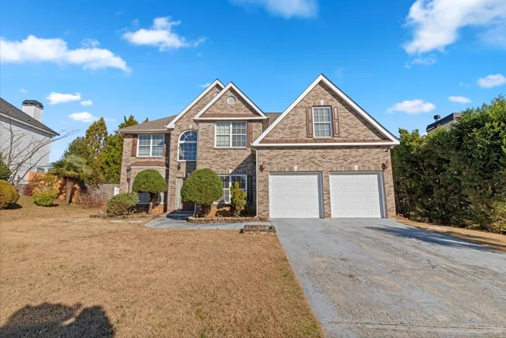 Brick facade with multiple gables, arched window, and a two-car garage