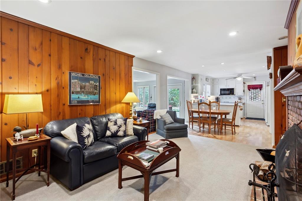 Living room with wood walls, light hardwood / wood-style floors, a fireplace, and ceiling fan Living room with wood walls, light hardwood / wood-style floors, a fireplace, and ceiling fan
