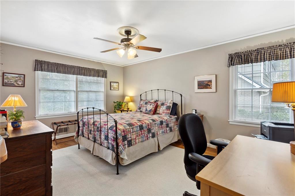Bedroom with ornamental molding, multiple windows, light hardwood / wood-style floors, and ceiling fan Bedroom with ornamental molding, multiple windows, light hardwood / wood-style floors, and ceiling fan