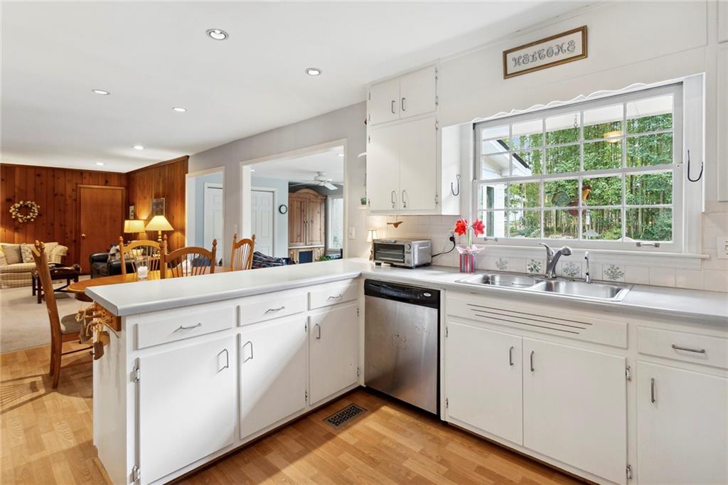 Kitchen with kitchen peninsula, white cabinets, stainless steel dishwasher, sink, and light wood-type flooring Kitchen with kitchen peninsula, white cabinets, stainless steel dishwasher, sink, and light wood-type flooring