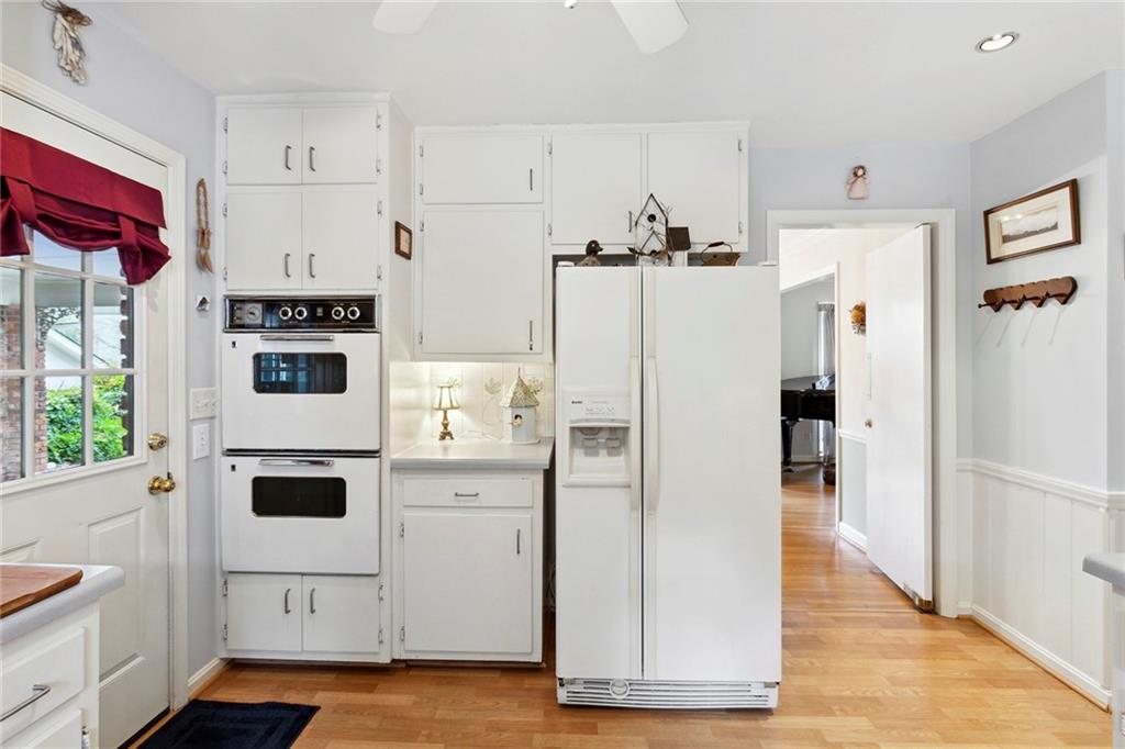 Kitchen featuring light hardwood / wood-style floors, white appliances, white cabinets, and backsplash Kitchen featuring light hardwood / wood-style floors, white appliances, white cabinets, and backsplash