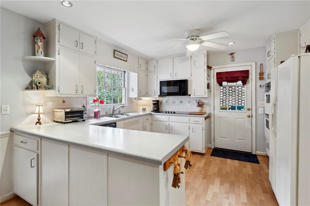 Kitchen featuring black appliances, tasteful backsplash, light hardwood / wood-style flooring, and ceiling fan Kitchen featuring black appliances, tasteful backsplash, light hardwood / wood-style flooring, and ceiling fan
