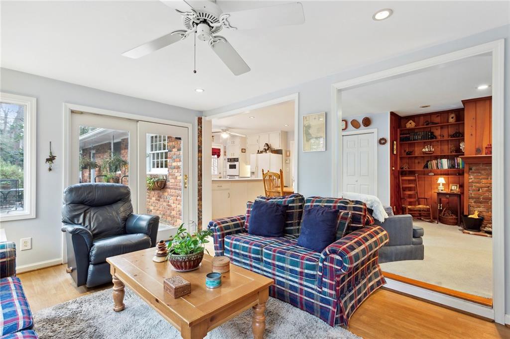 Living room featuring built in shelves, light hardwood / wood-style floors, and ceiling fan Living room featuring built in shelves, light hardwood / wood-style floors, and ceiling fan