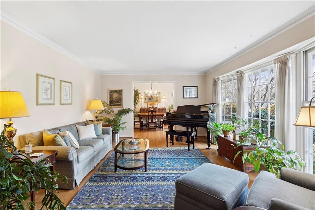 Living room with ornamental molding, light wood-type flooring, and a notable chandelier Living room with ornamental molding, light wood-type flooring, and a notable chandelier