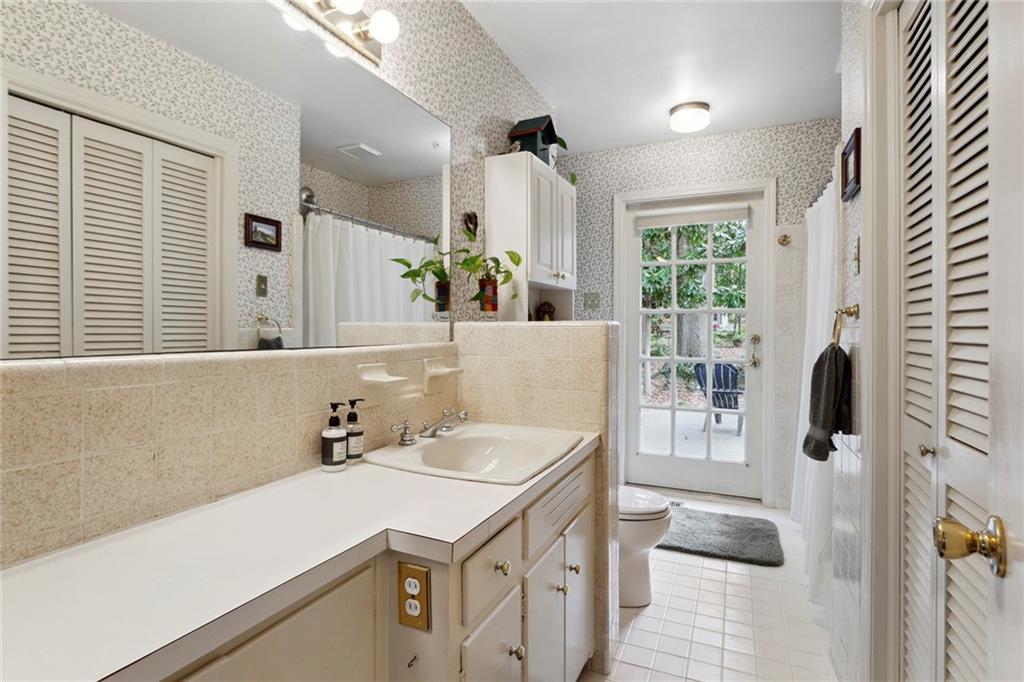 Bathroom with a chandelier, vanity, toilet, and tile flooring Bathroom with a chandelier, vanity, toilet, and tile flooring