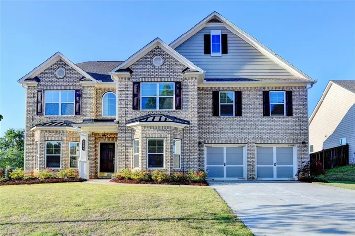 View of front of home featuring brick siding, driveway, and a garage